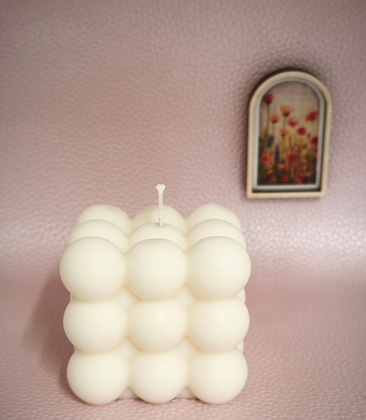 Bougie moulée ORBI blanc cassé de Cirélise : bougie multiboules sur fond rose avec petit cadre fleuri
