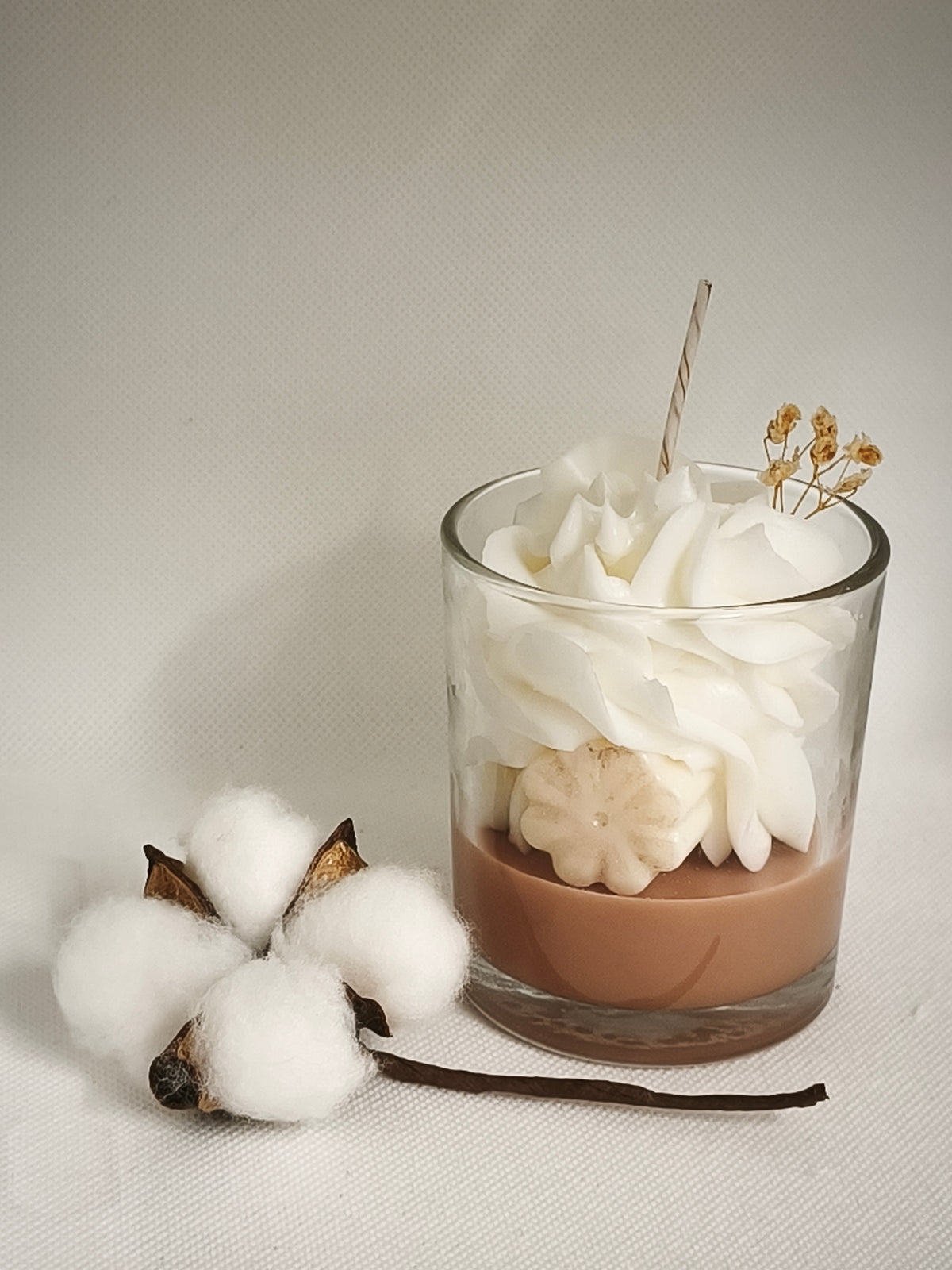 Bougie Fleur de Coton en verre à côté d’une branche de coton
