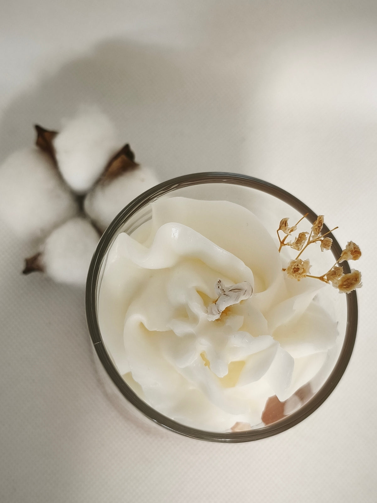 Vue du dessus de la bougie Fleur de Coton et de son décor blanc effet chantilly